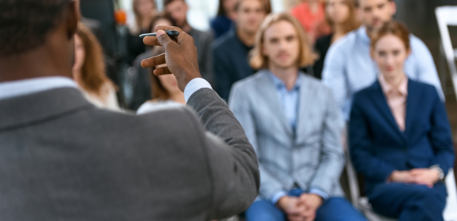 Person står på en konferens eller seminarium och talar för en sittande publik